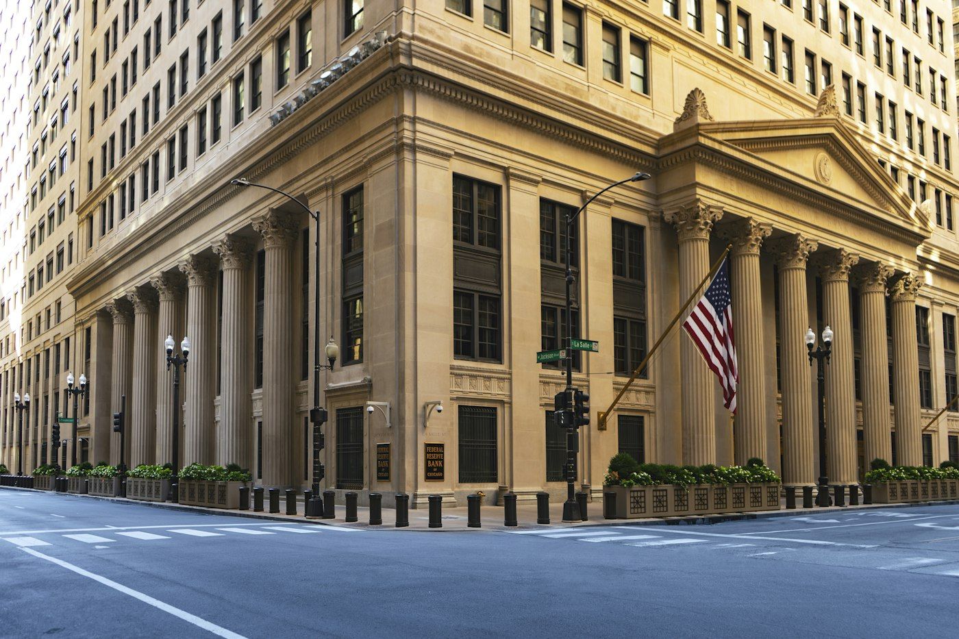 Classical stone facade of a Federal Reserve Bank building with columns and an American flag