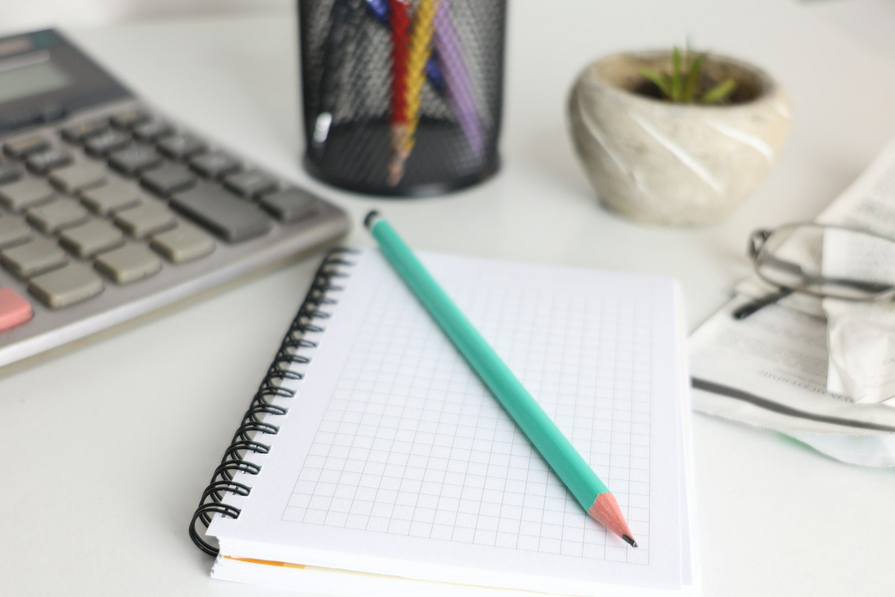 Calculator, grid notebook and pencil on a tidy desk, ready for a family office monthly close