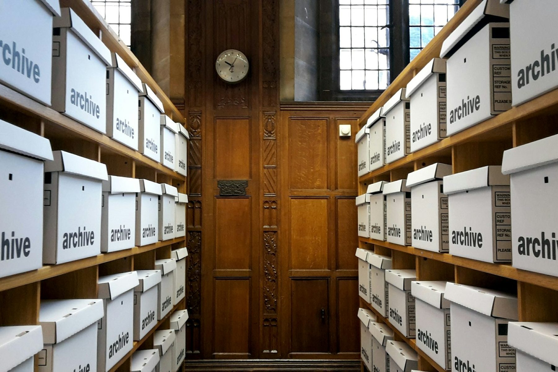 Records room lined with archive boxes on wooden shelves, the long-term record-keeping a single-family office maintains